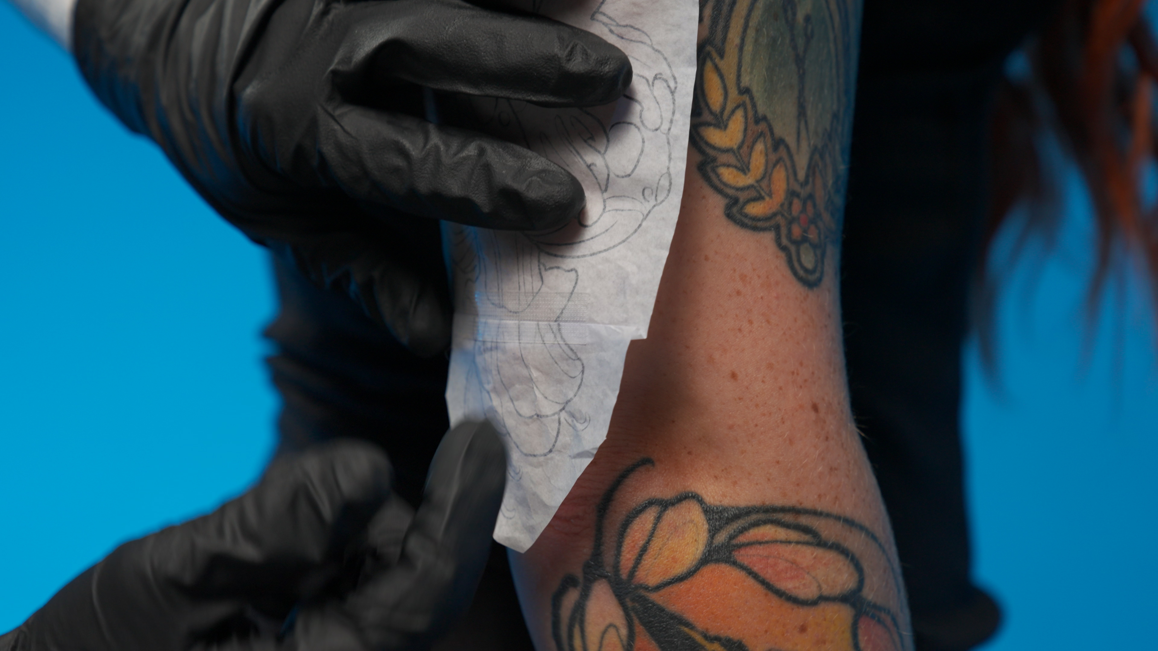 Stencil being carefully applied to skin, the precision before the needle